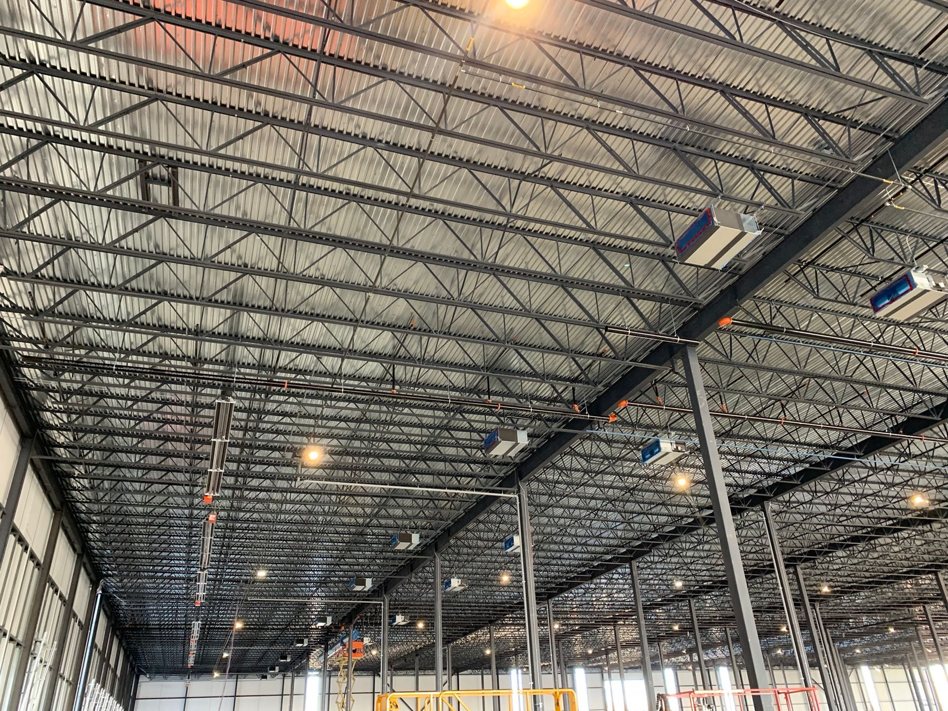 Une personne vêtue d'un sweat-shirt orange, agenouillée sur un trottoir, vérifie l'état d'un petit chiot brun assis en laisse.