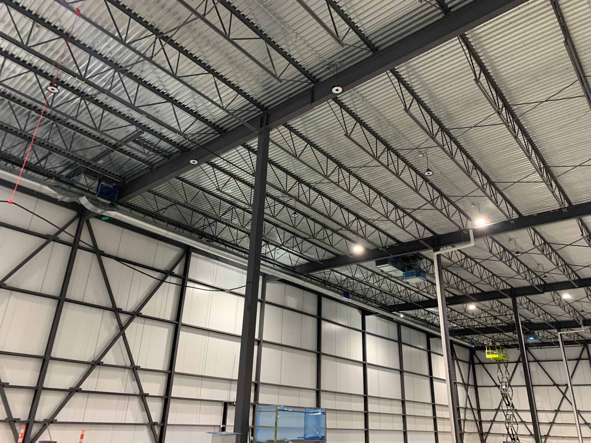 Intérieur d'un grand entrepôt industriel avec charpente métallique et panneaux muraux blancs