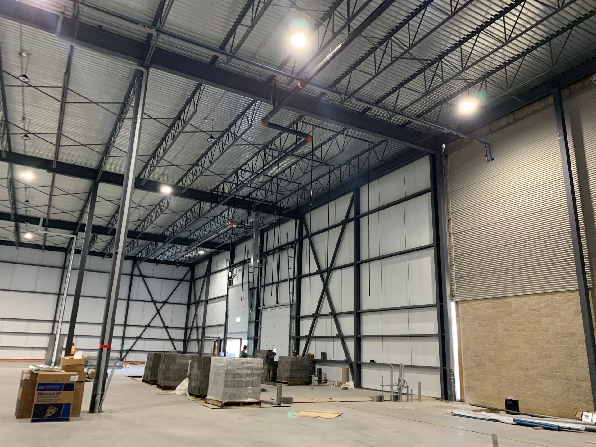 Une personne vêtue d'un sweat-shirt orange, agenouillée sur un trottoir, vérifie l'état d'un petit chiot brun assis en laisse.