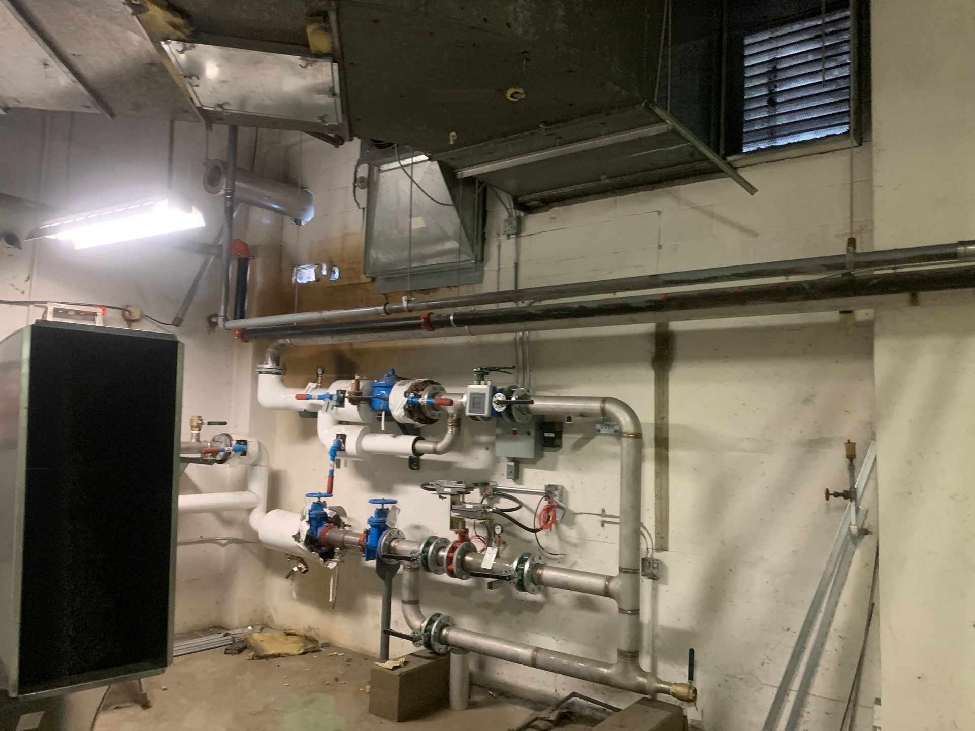 Une personne vêtue d'un sweat-shirt orange, agenouillée sur un trottoir, vérifie l'état d'un petit chiot brun assis en laisse.