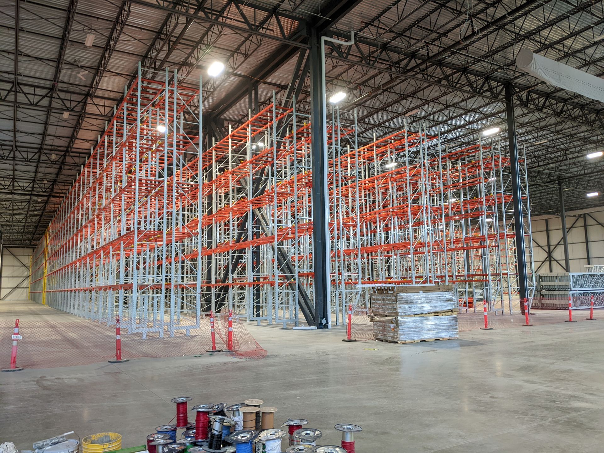 Intérieur d'entrepôt avec d'imposantes étagères de stockage orange et grises et des palettes empilées au sol