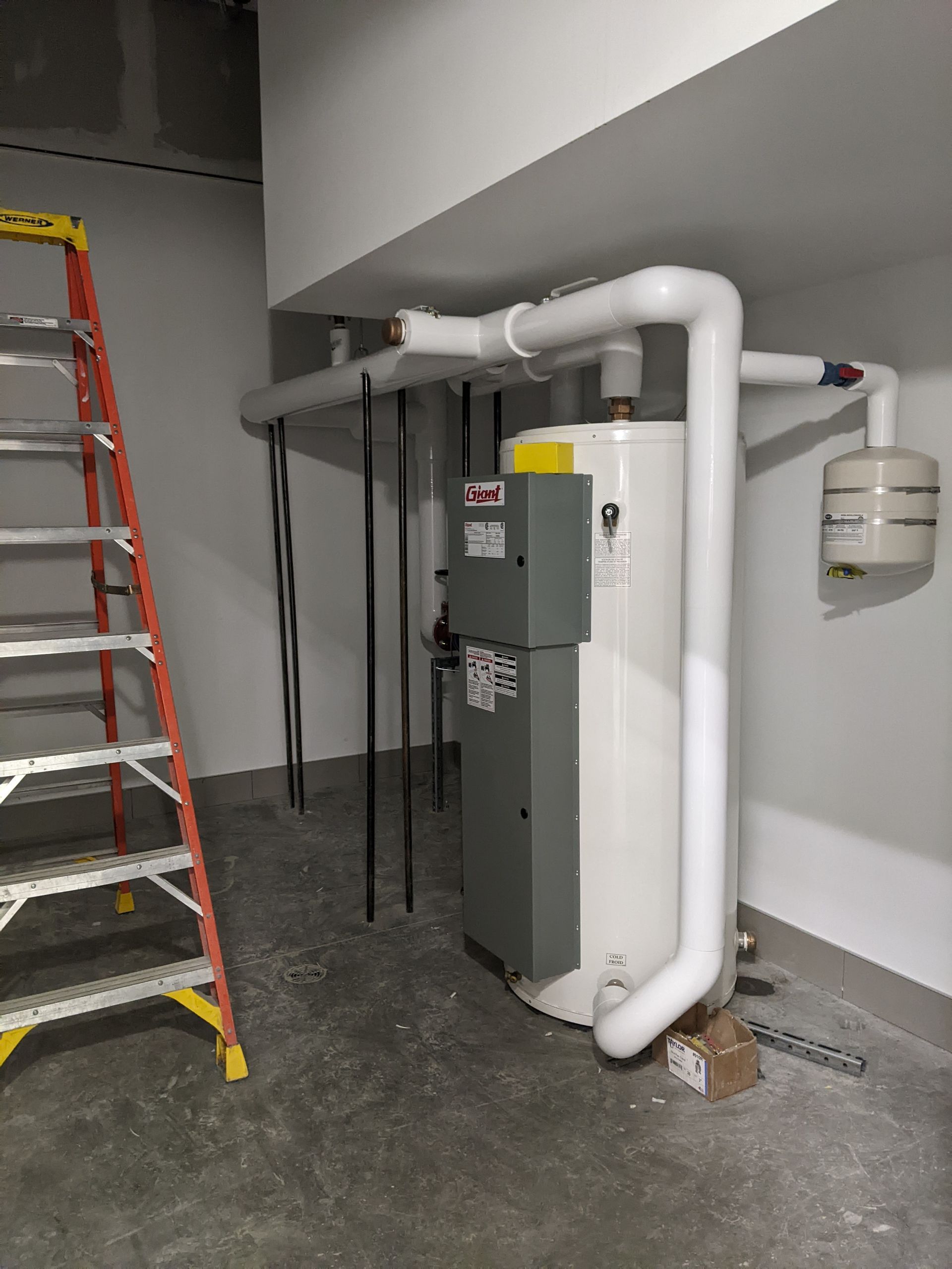 Une personne vêtue d'un sweat-shirt orange, agenouillée sur un trottoir, vérifie l'état d'un petit chiot brun assis en laisse.