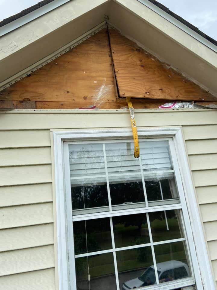 Exposed plywood under a roof eave above a window, showing potential water damage.