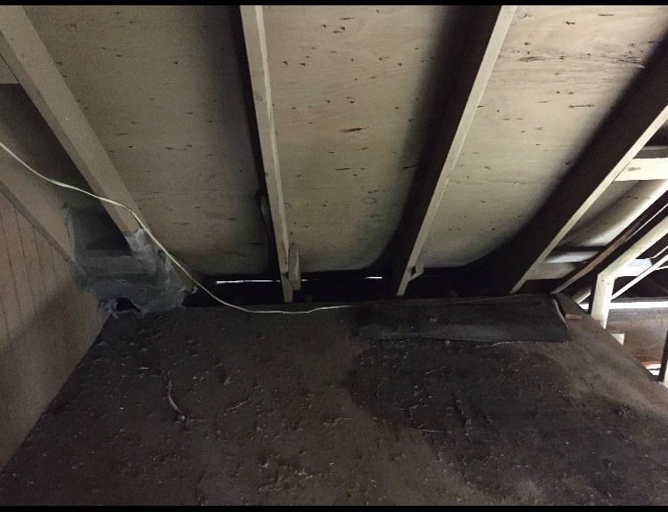 View from below a concrete ceiling with support beams and electrical wiring.