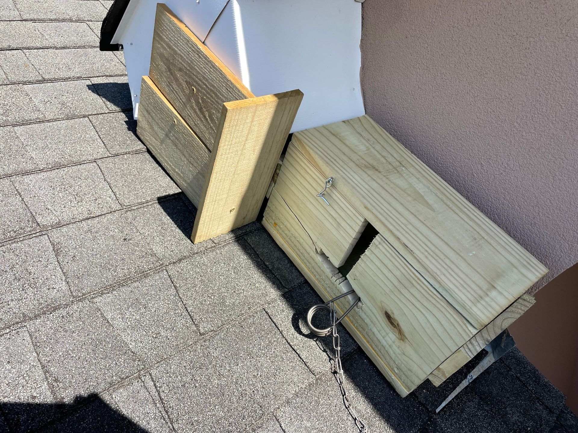 Wooden boards and metal hardware on a shingled roof, likely part of a DIY repair or project.