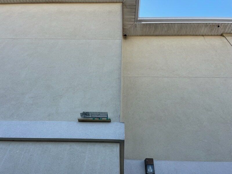 Beige building exterior with two sections, and a security camera near the roof.