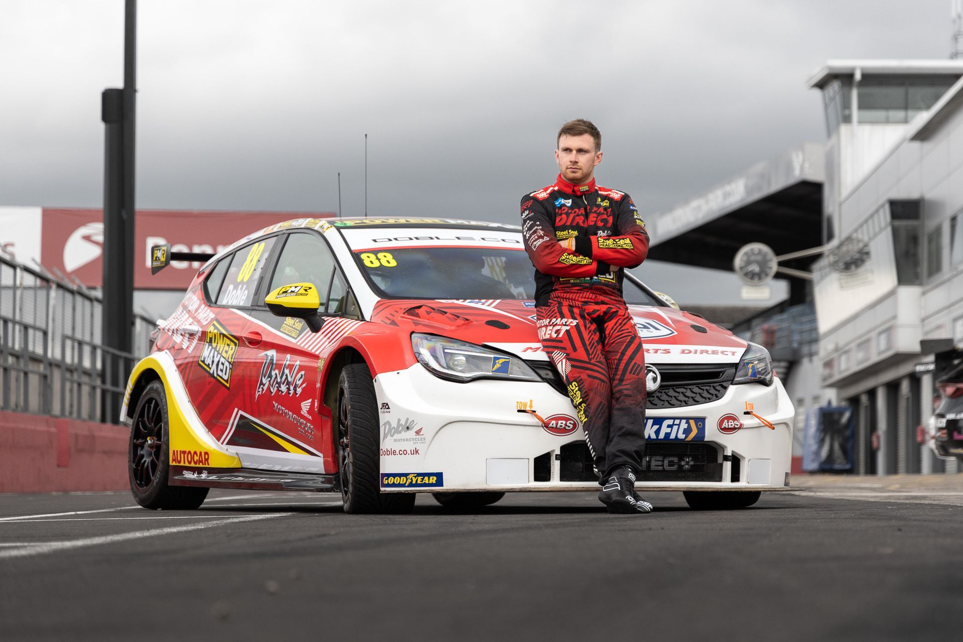 A man is standing next to a race car on a track.