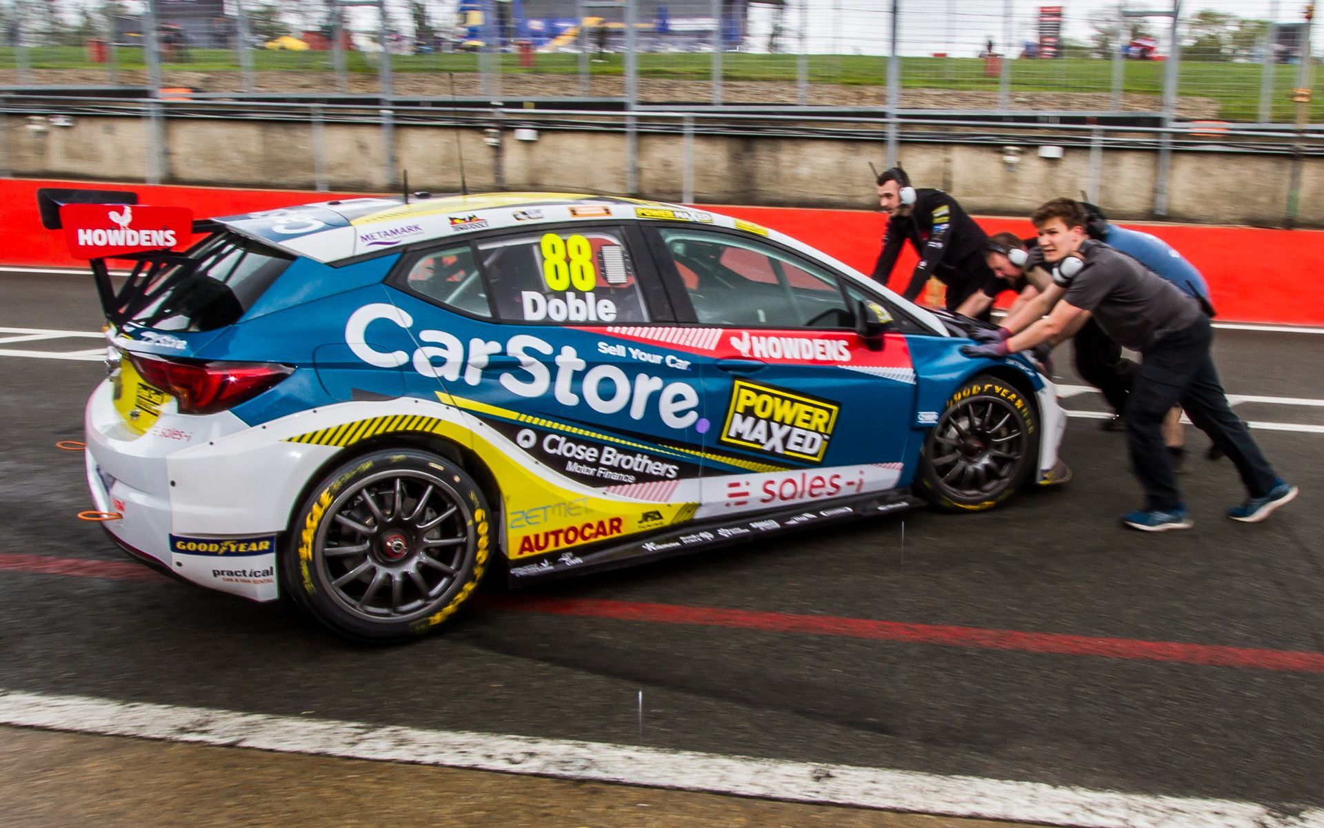 A race car with the number 88 on the side is being pushed by people.