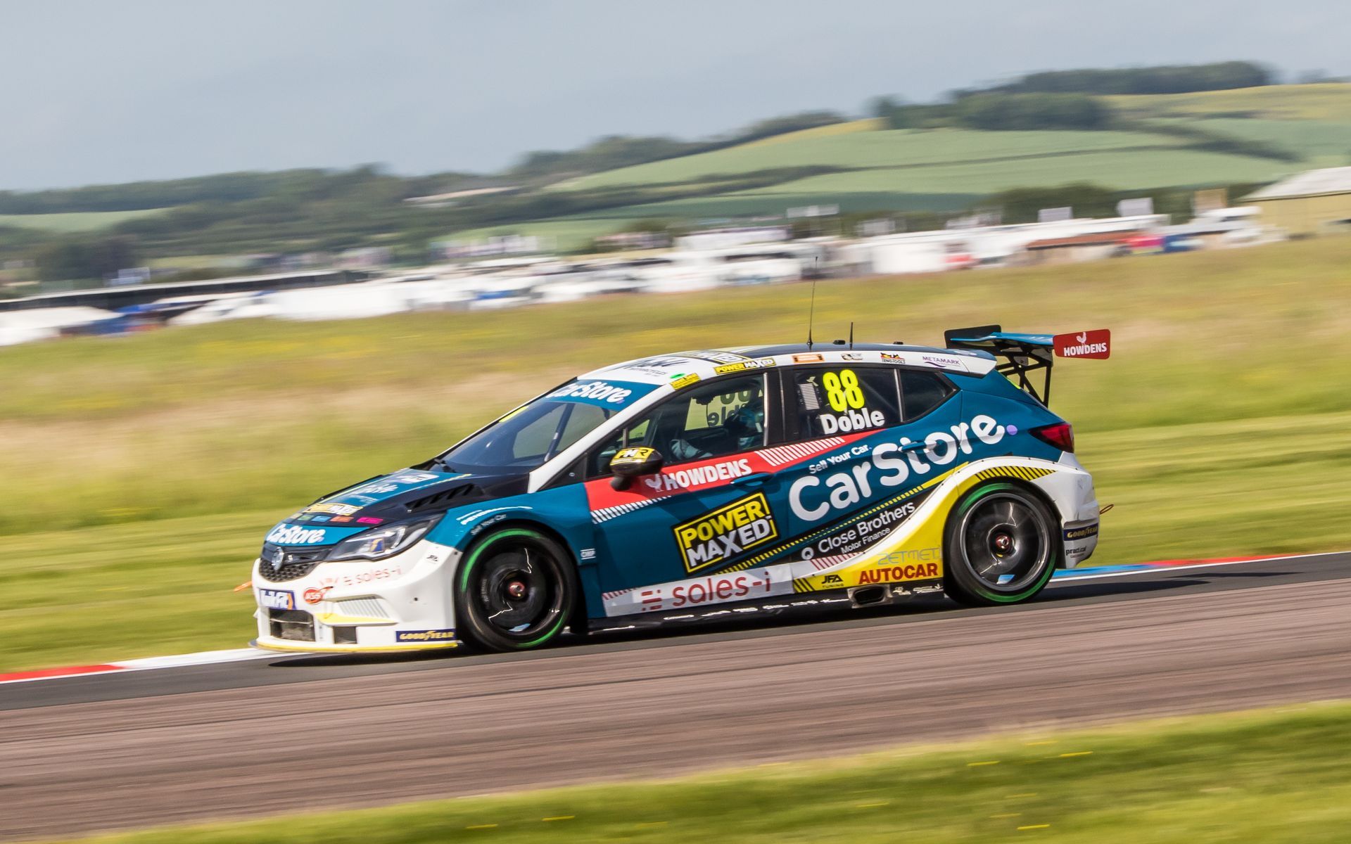 A racing car is driving down a race track.