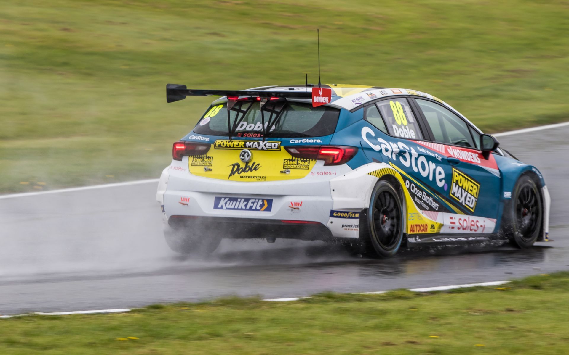 A race car is driving down a wet track.