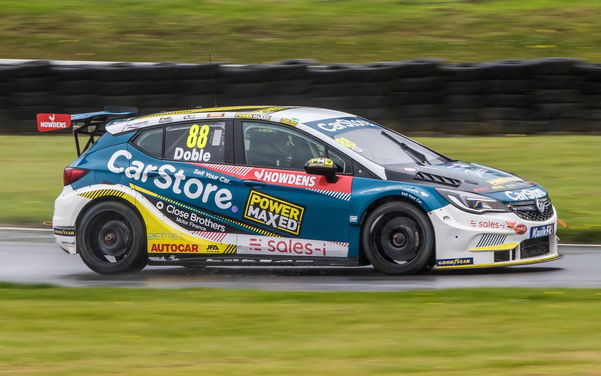 A blue and yellow race car is driving down a track.
