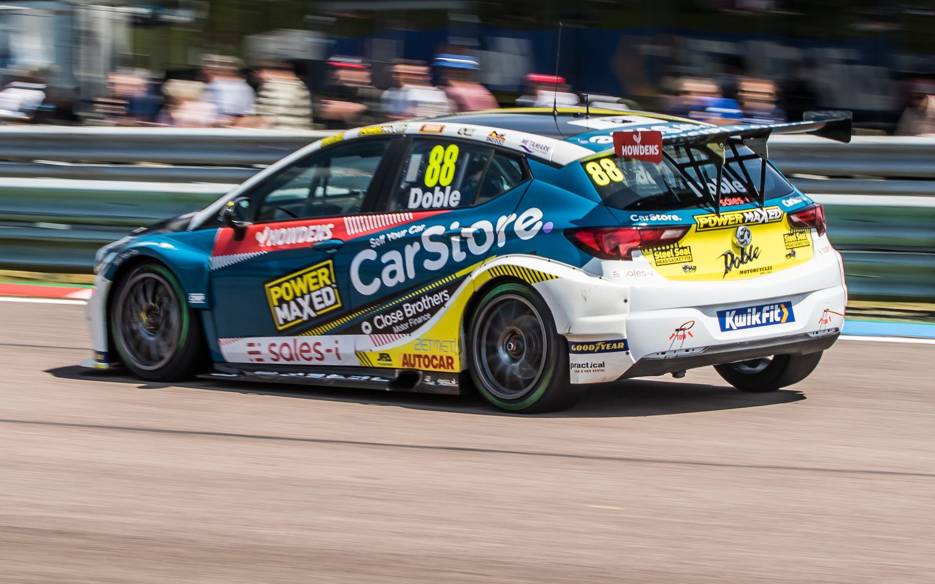 A blue and yellow race car is driving down a race track.