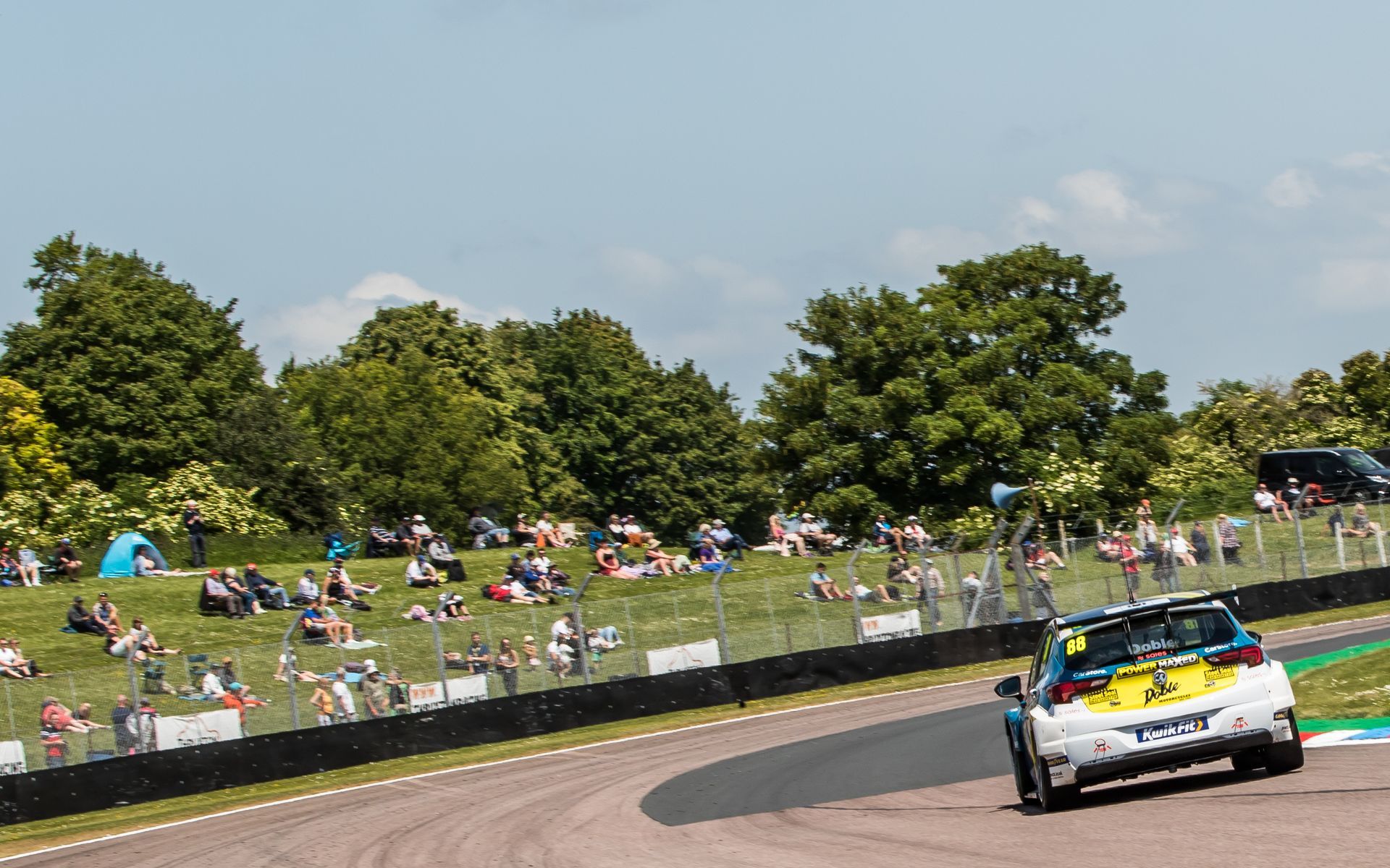 A race car is driving down a track in front of a crowd of people.