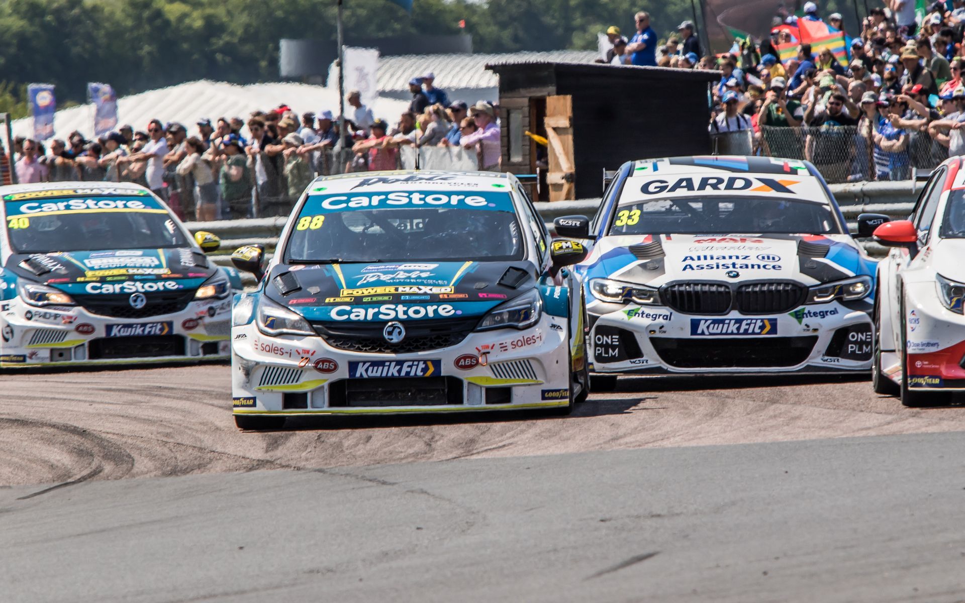 A group of racing cars are driving down a race track.