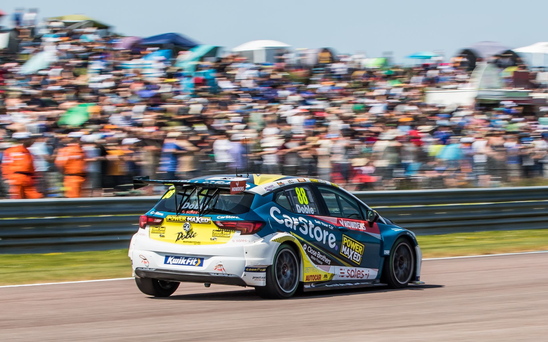 A race car is driving on a race track in front of a crowd.