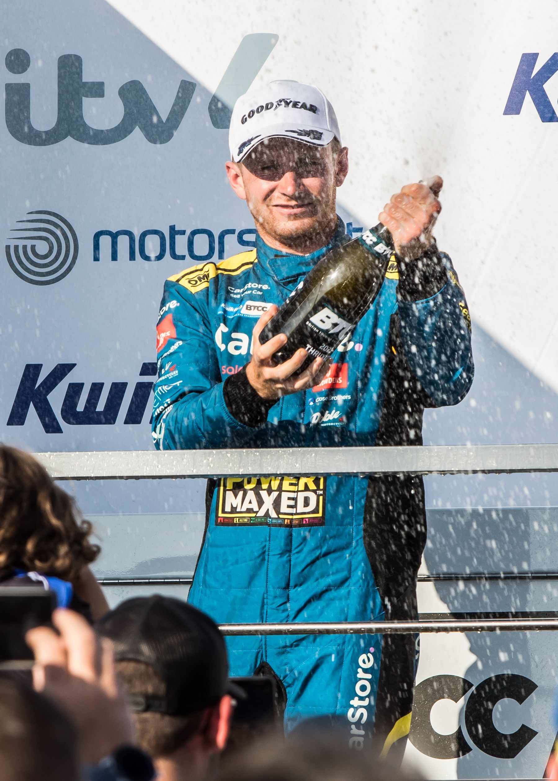 A man in a blue suit is holding a bottle of champagne