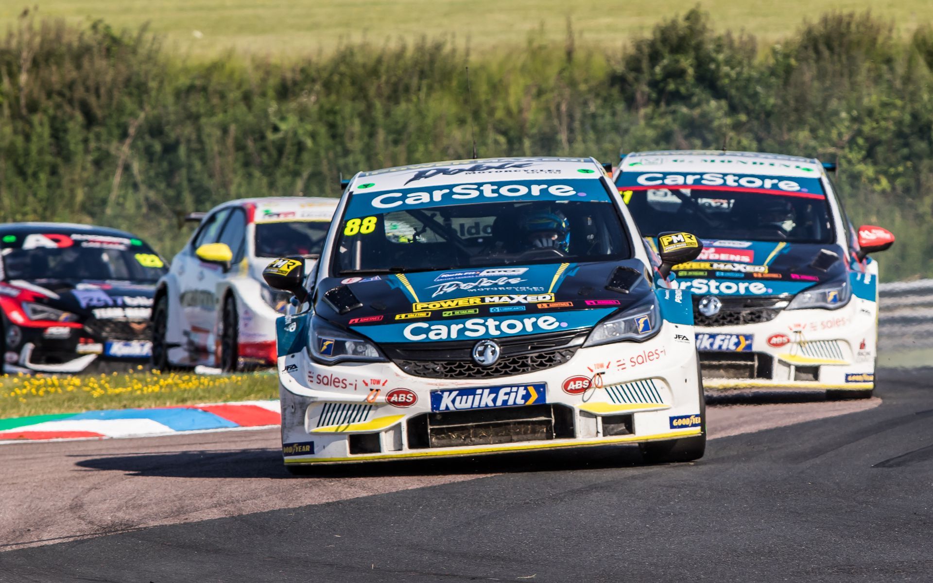 A group of racing cars are driving down a race track.