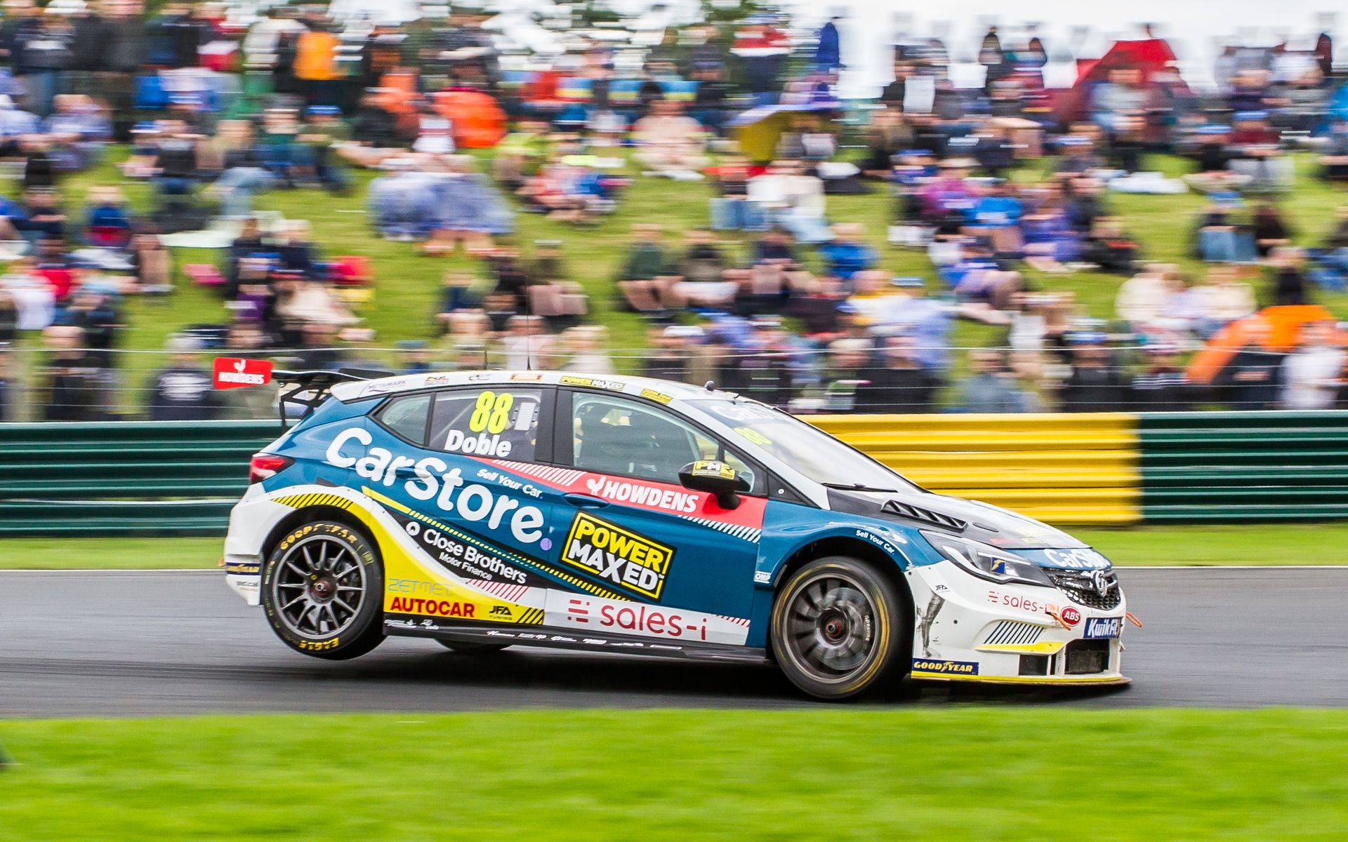 A race car is driving on a race track in front of a crowd.