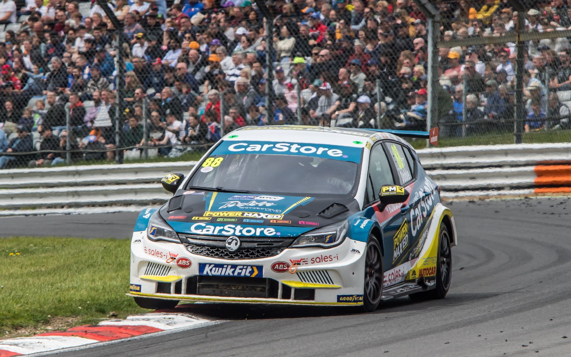 A race car is driving down a race track in front of a crowd.