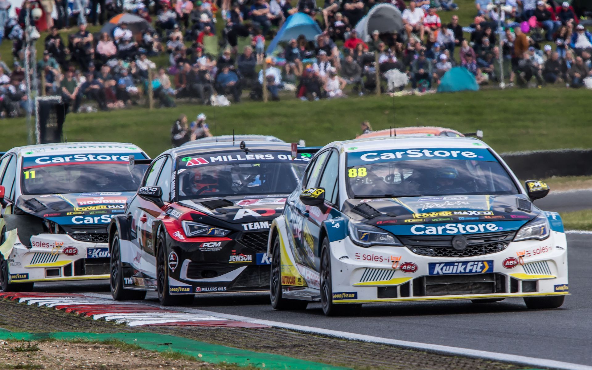 A group of cars are racing on a race track.