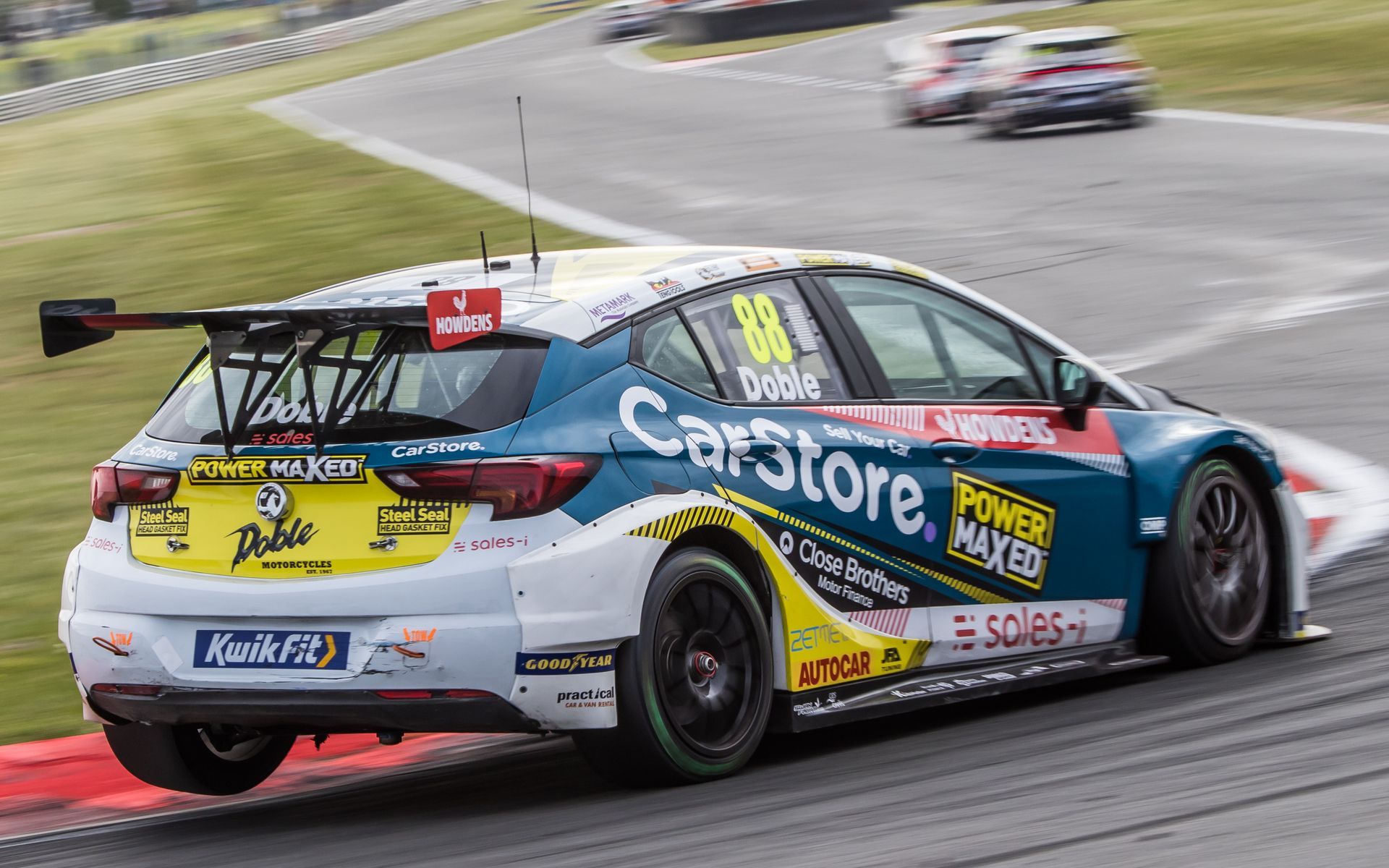 A blue and white race car is driving down a race track.