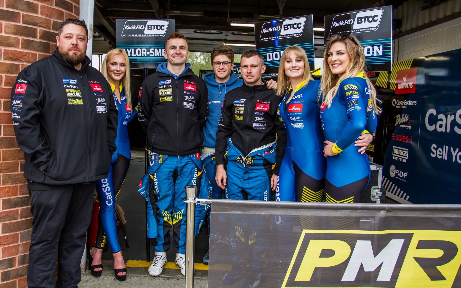 A group of people are posing for a picture in front of a sign that says pmr.