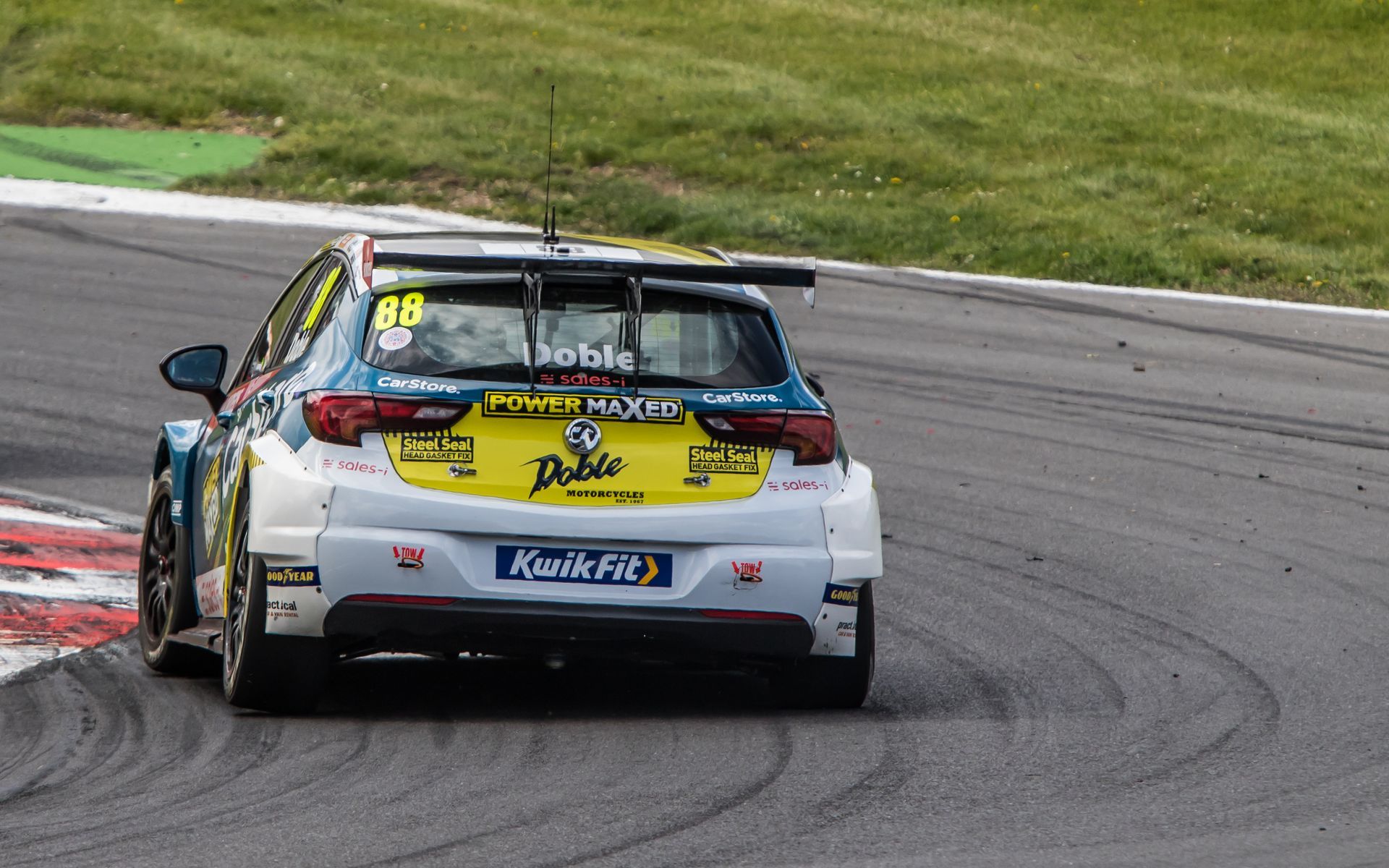 A race car is driving down a track with the number 68 on the back.