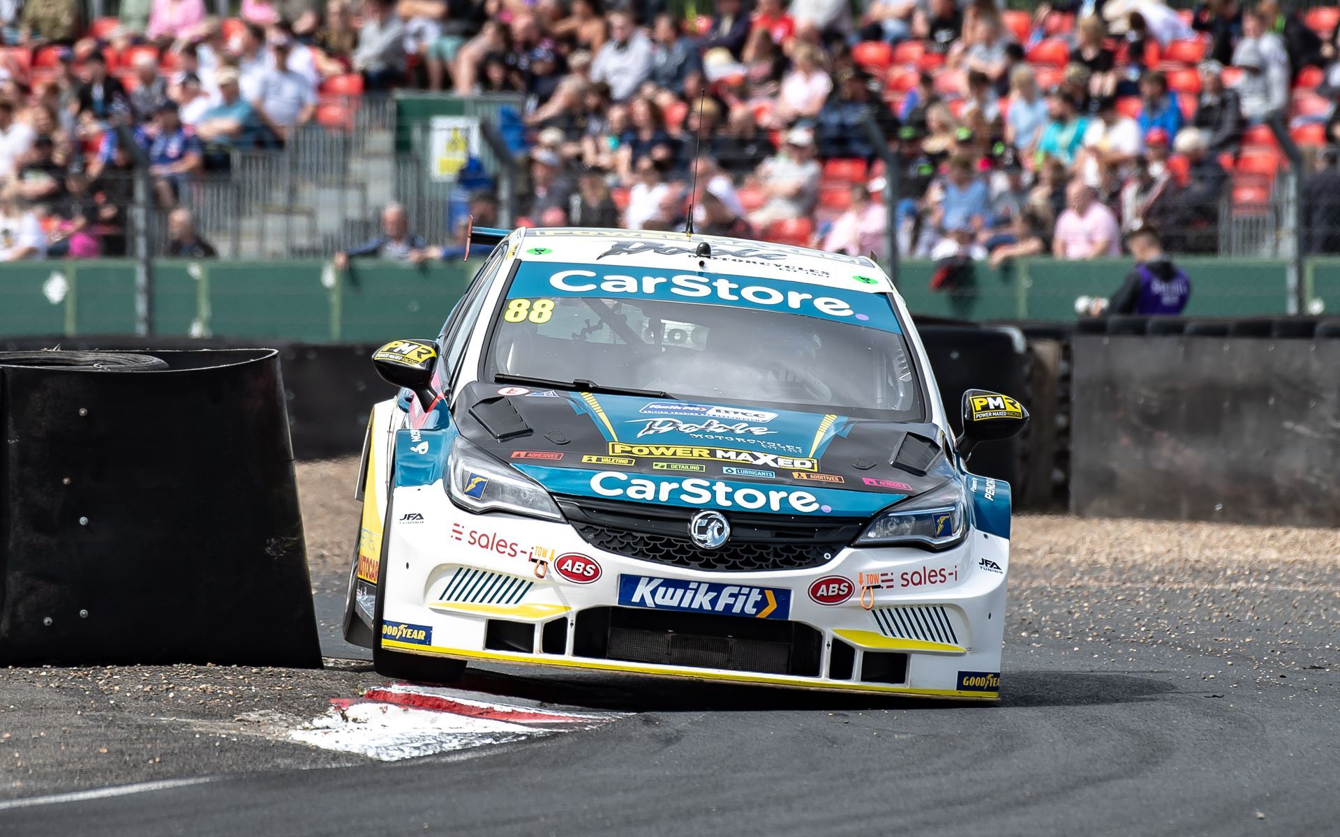 A race car is driving down a track in front of a crowd.