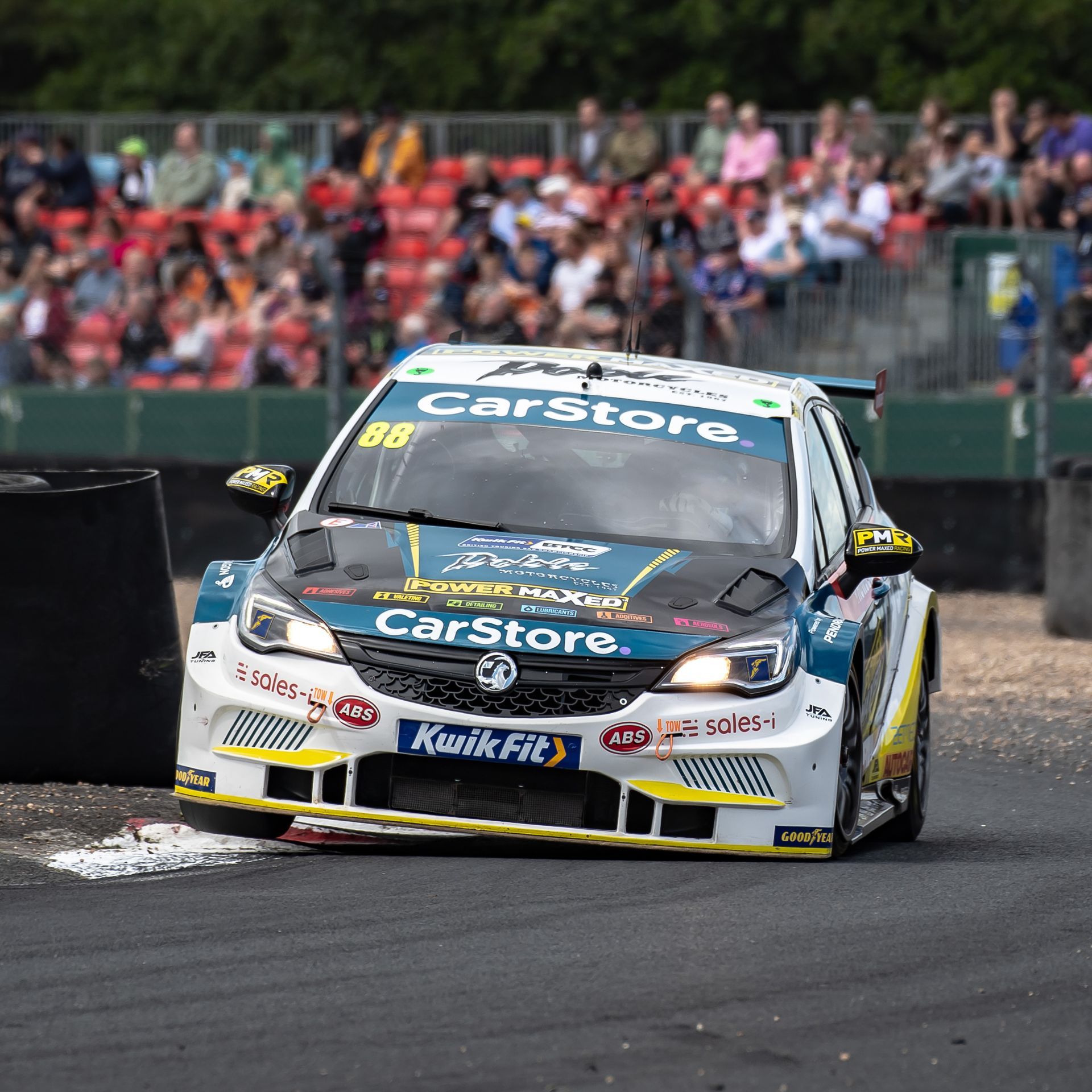 A race car with the word carstore on the front is driving down a track.