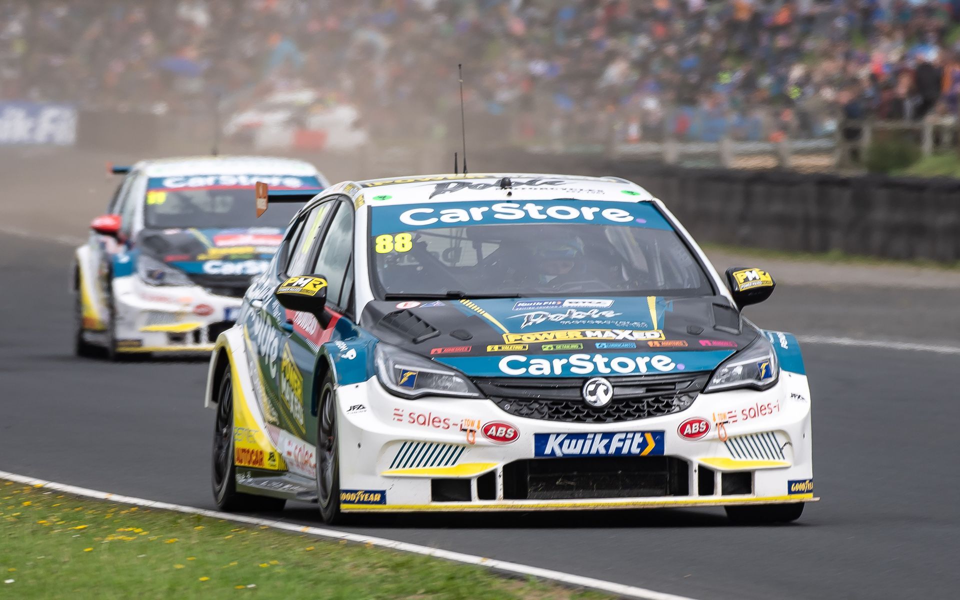 Two racing cars are driving down a race track.