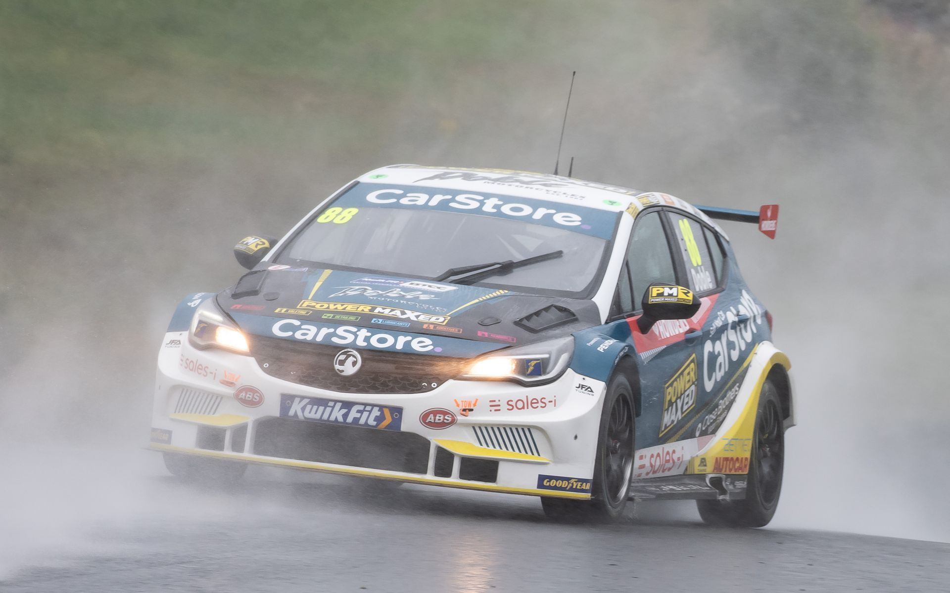 A race car is driving down a wet road in the rain.