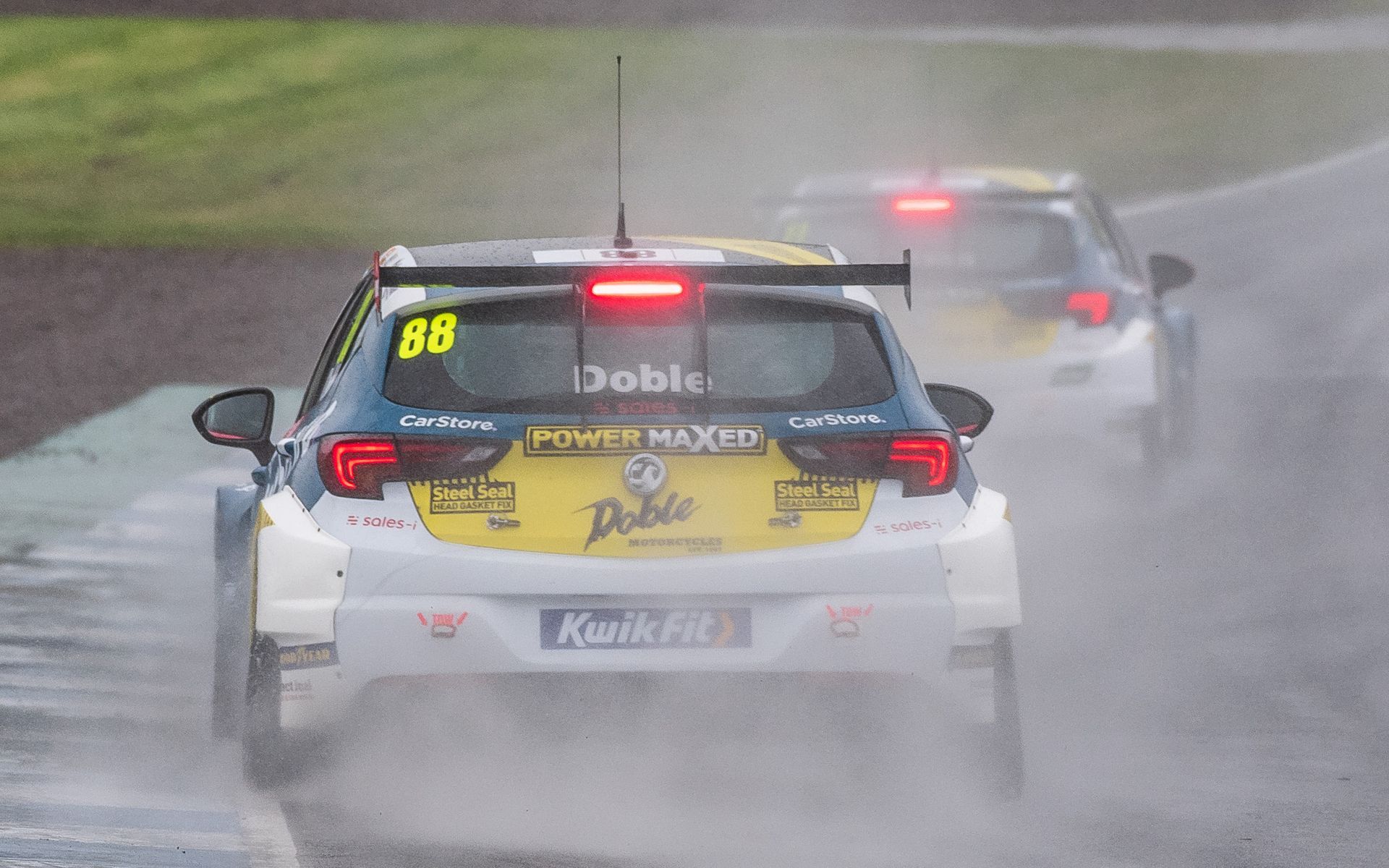 A race car is driving down a wet road in the rain.