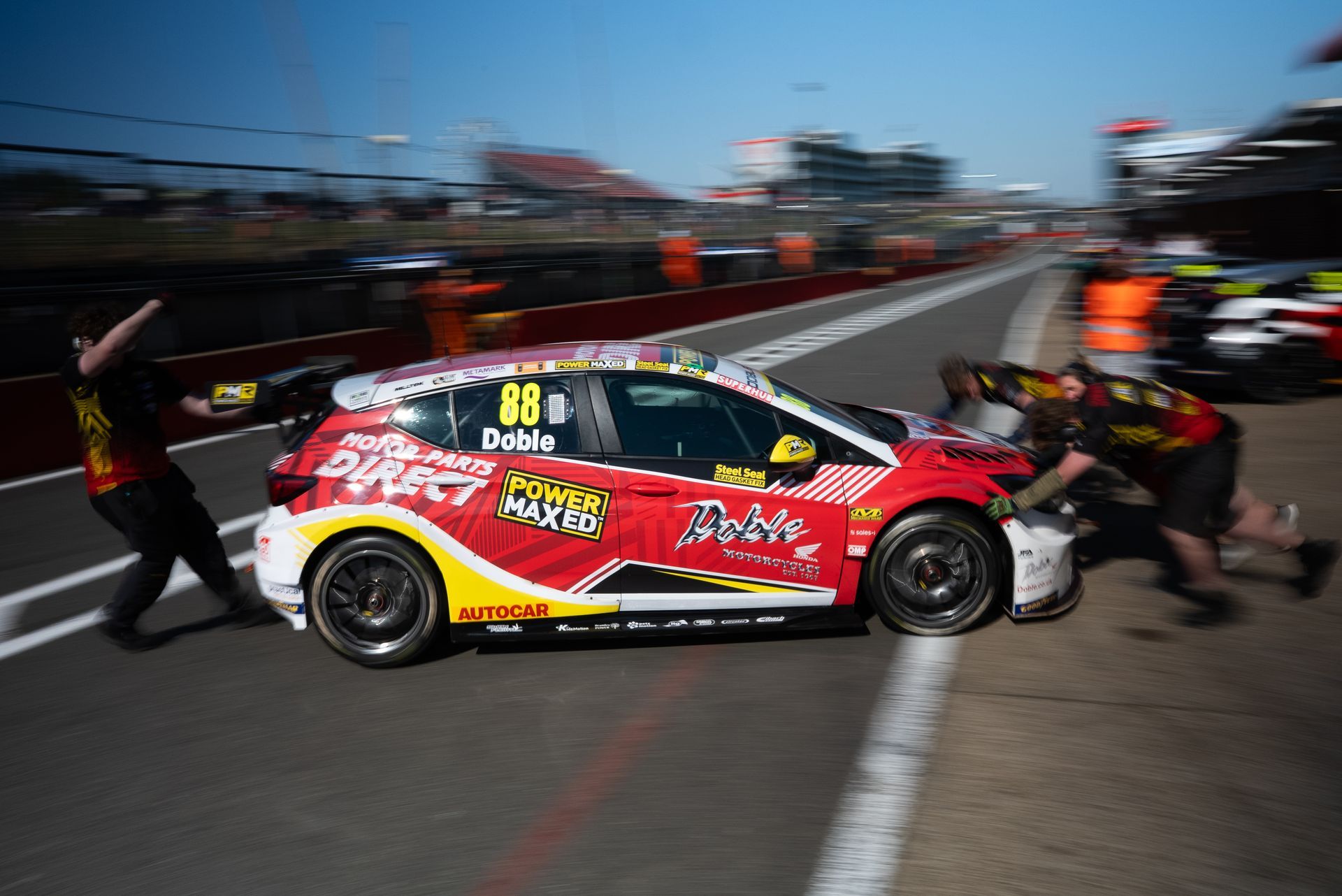 A red and yellow race car is parked on the side of a road.