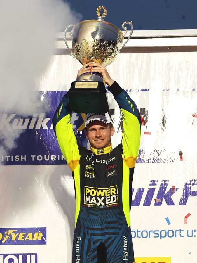 A man in a power maxed shirt is holding a trophy