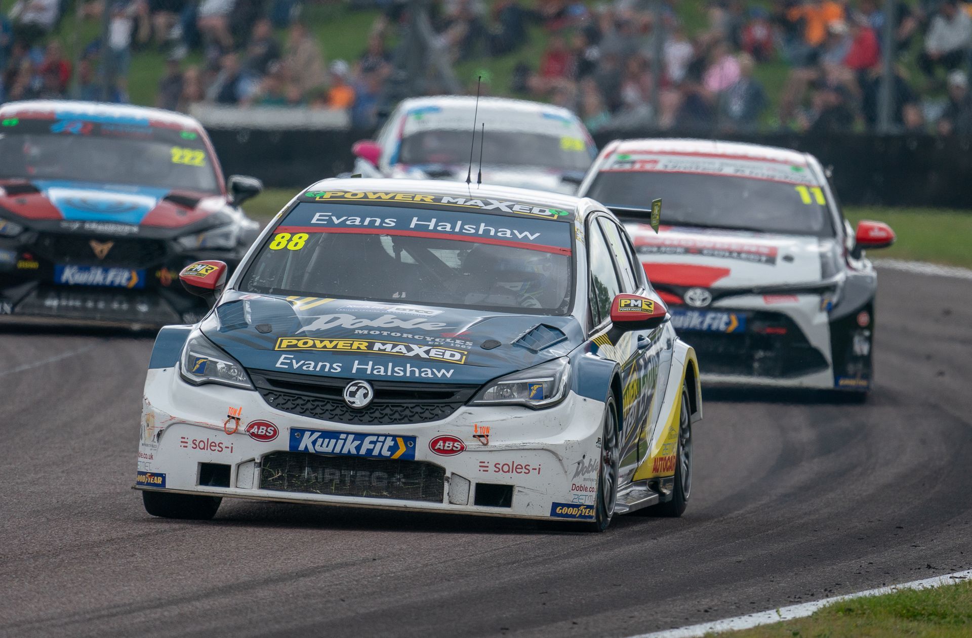 A group of racing cars are driving down a race track.