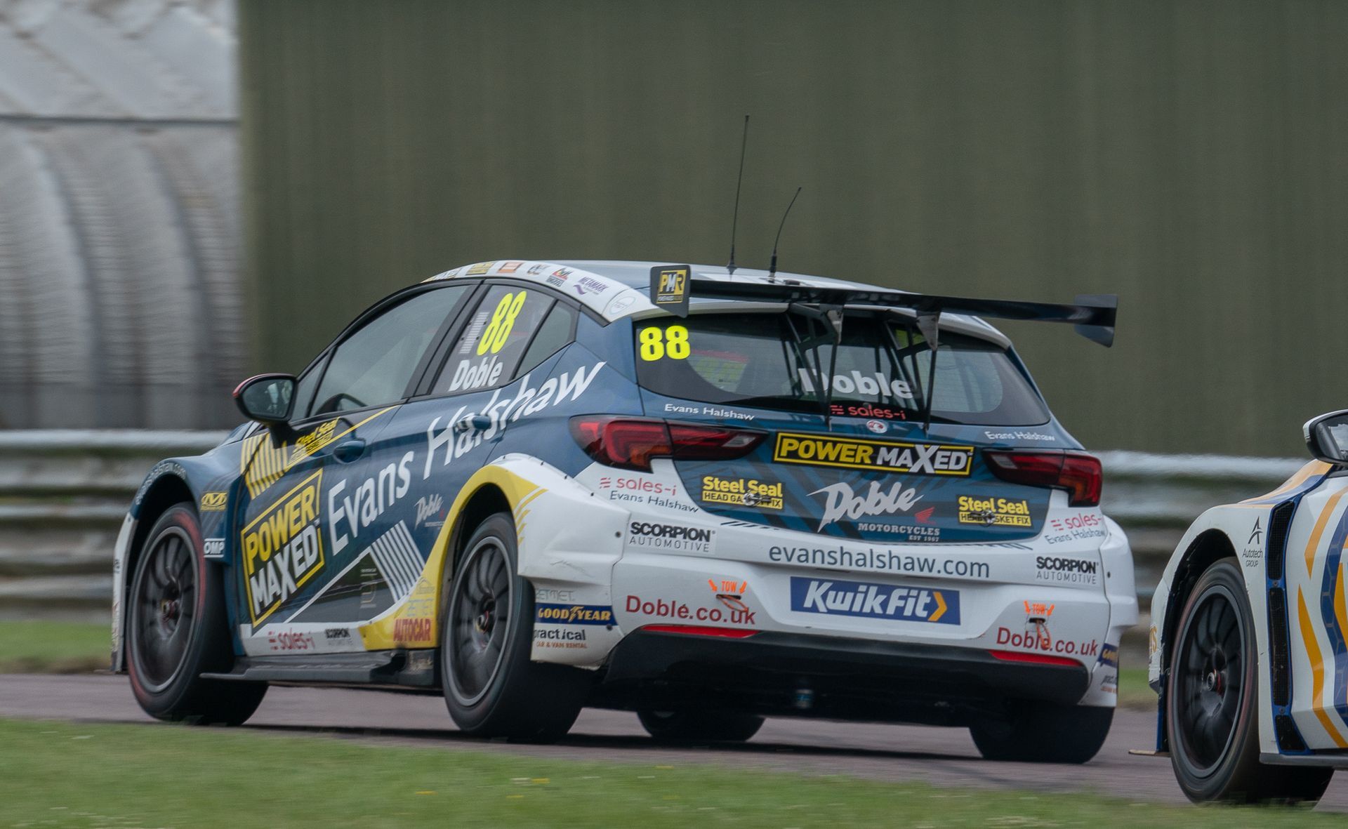 A race car is driving down a track next to another race car.
