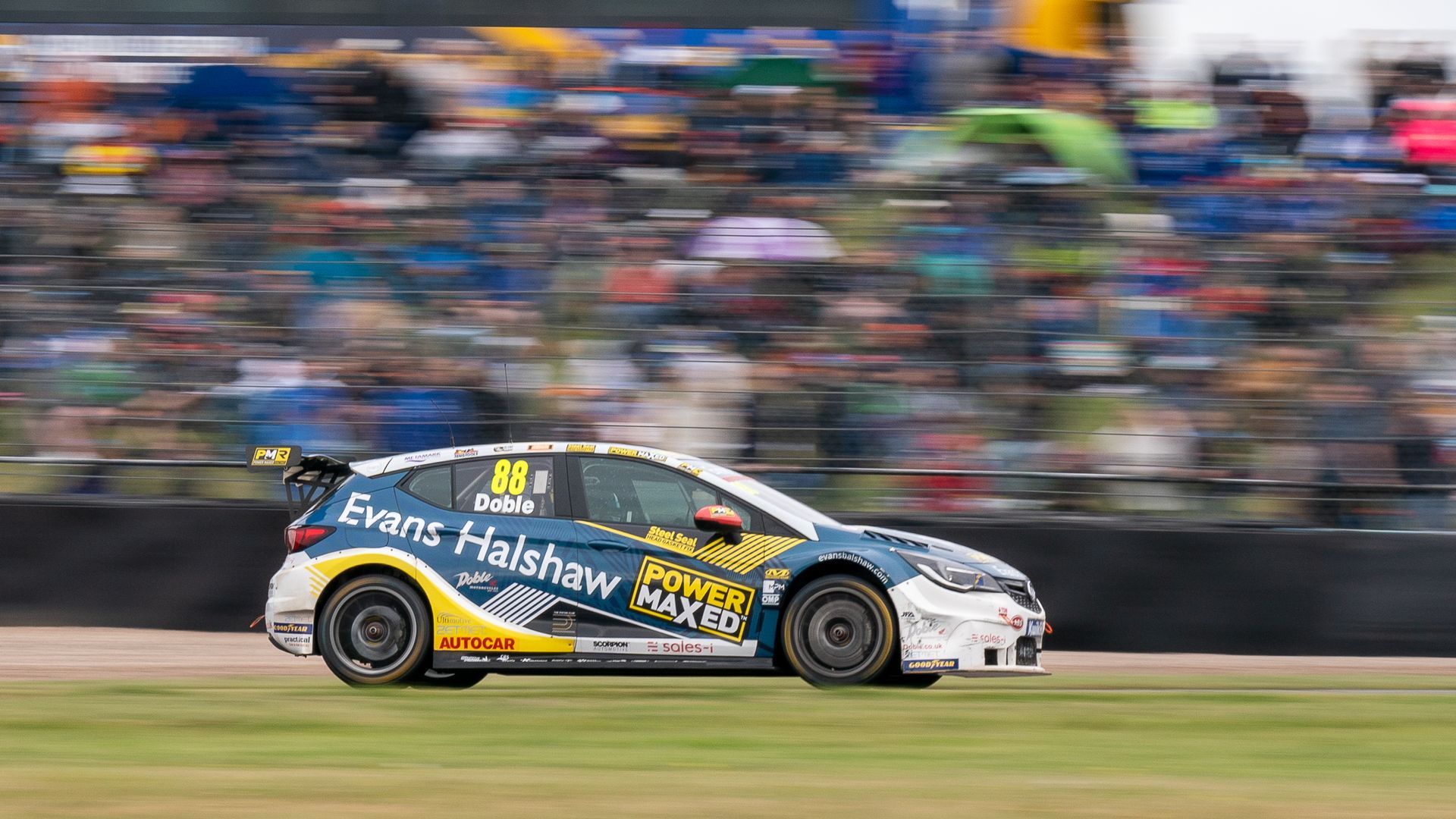 A race car is driving on a track in front of a crowd.