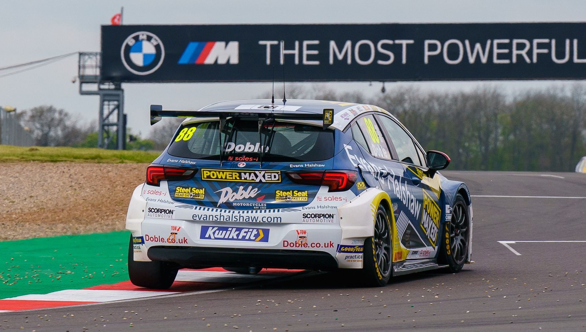 A race car is driving down a race track in front of a sign that says bmw the most powerful
