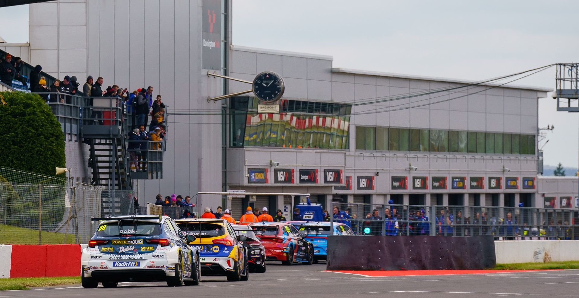 A group of cars are driving down a race track.
