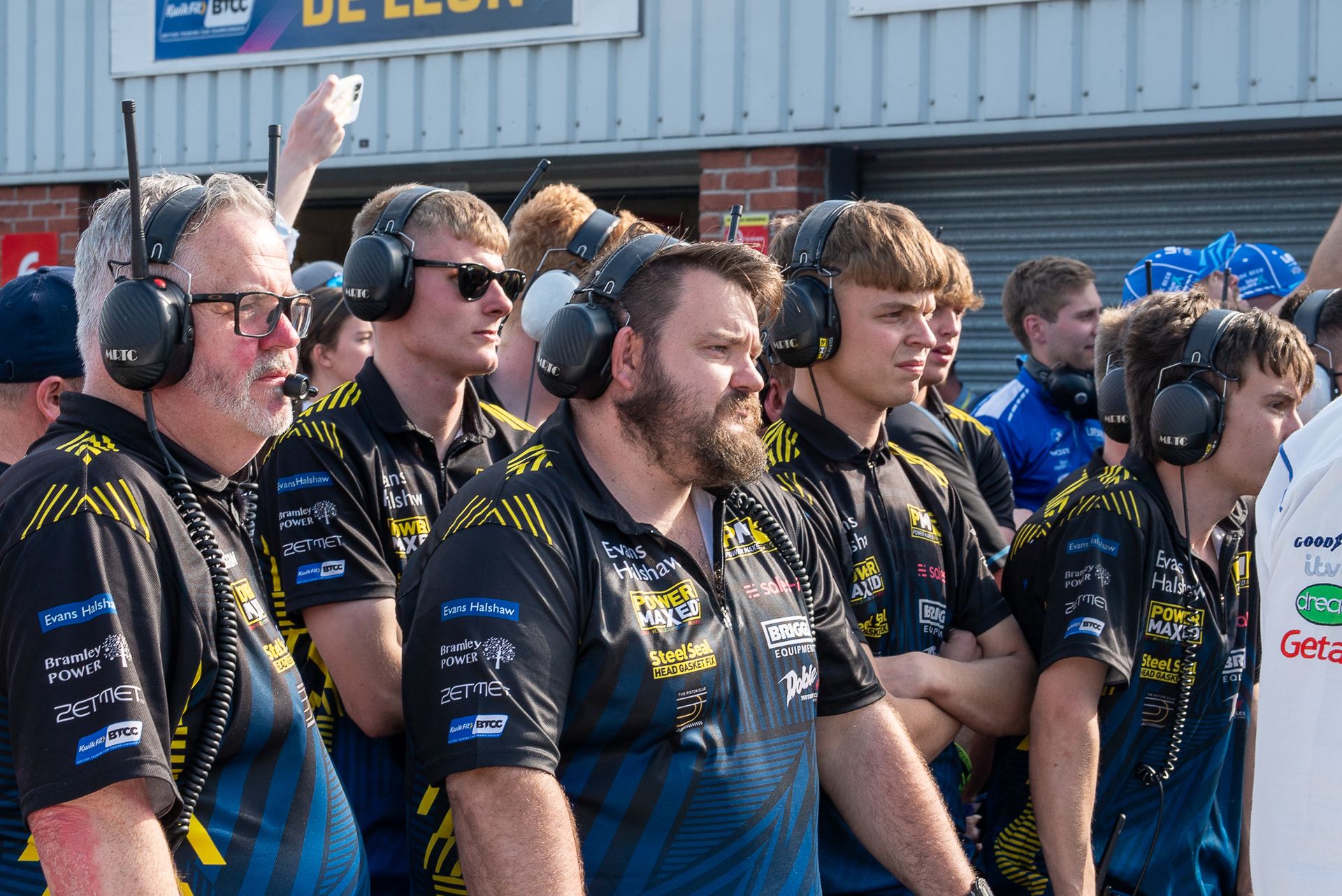 A group of men wearing headphones are standing in front of a building.