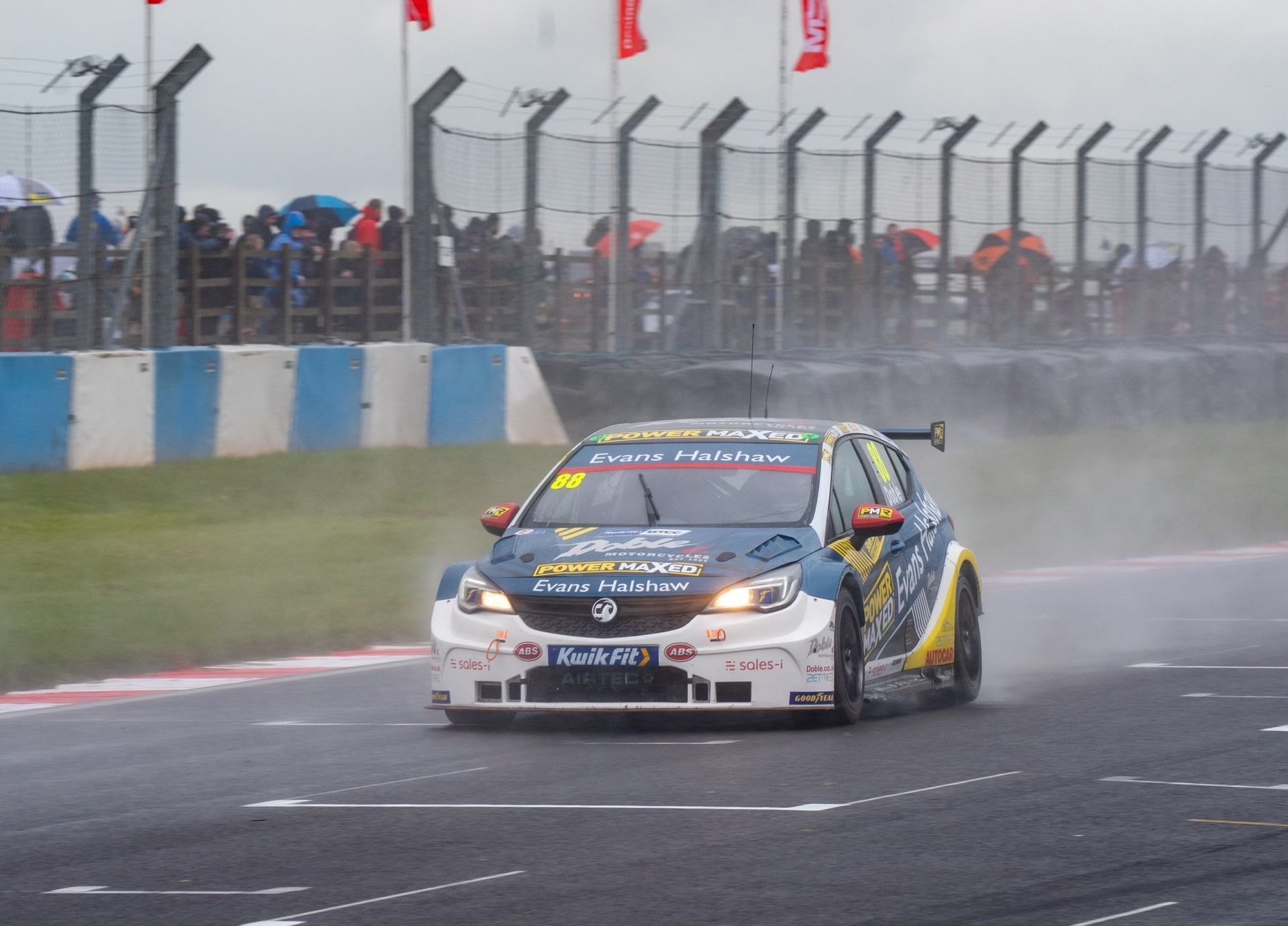 A race car is driving down a race track in the rain