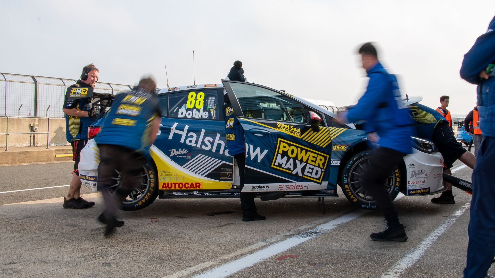 A group of people are working on a race car on a track.