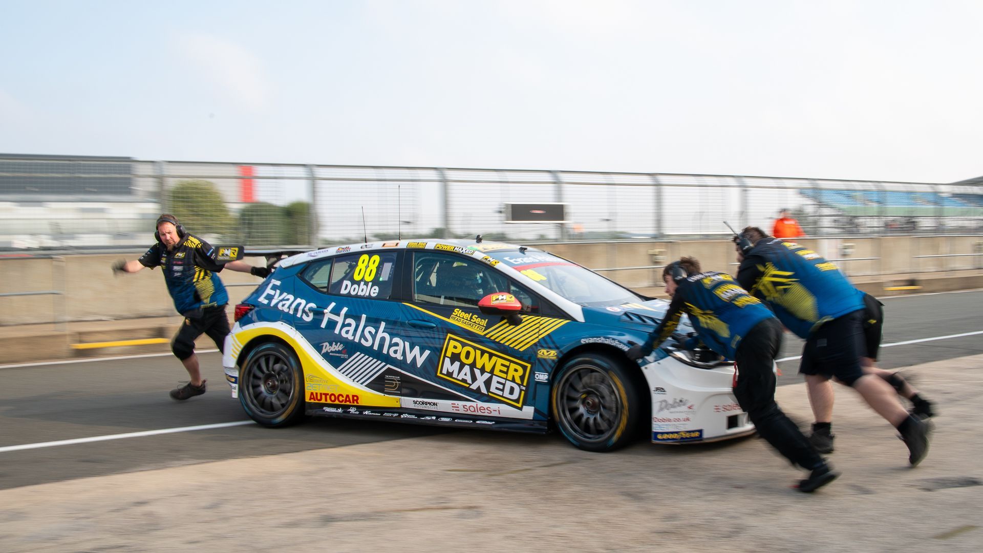 A group of men are pushing a race car on a track.