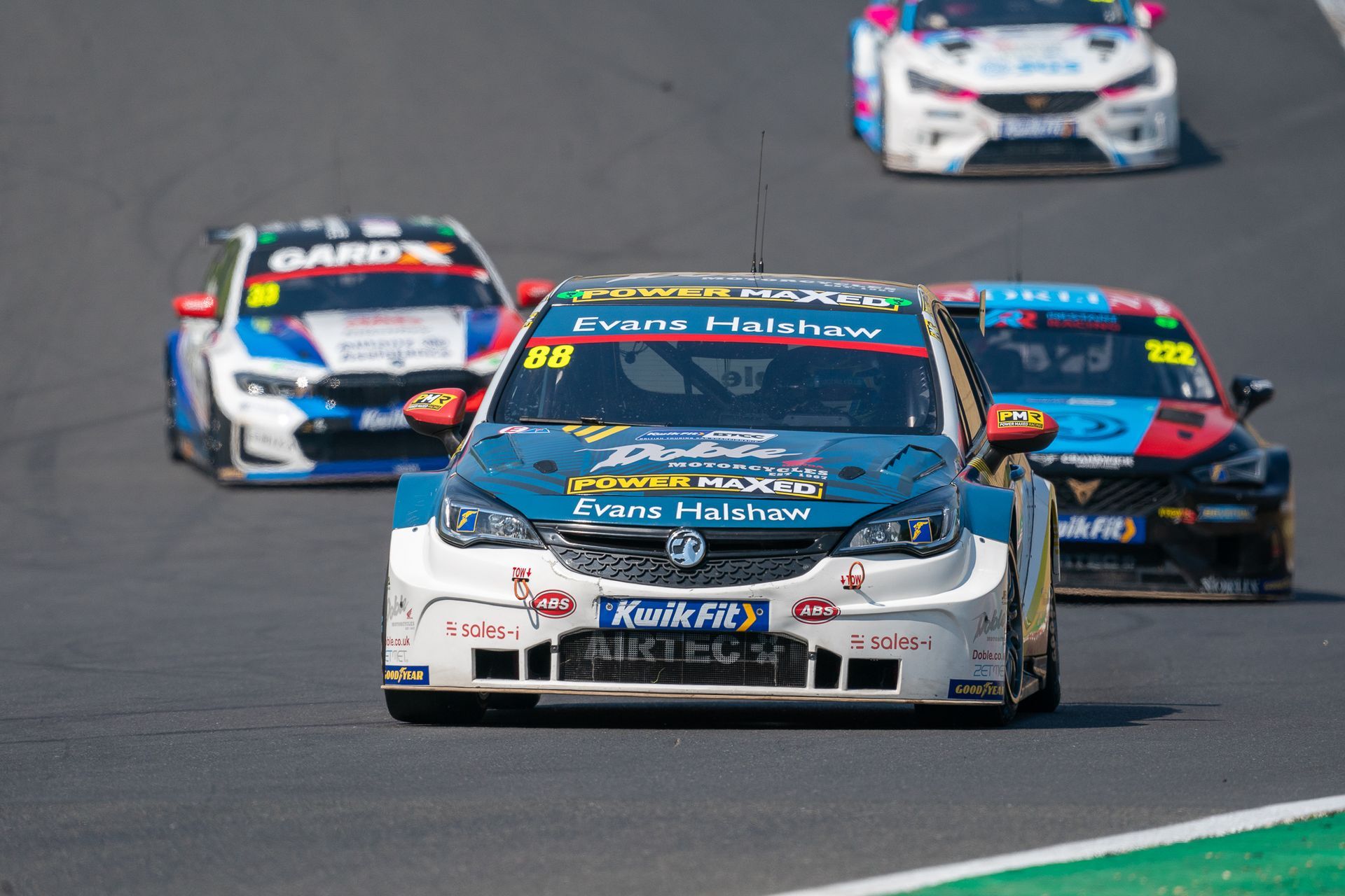 A group of racing cars are driving down a race track.
