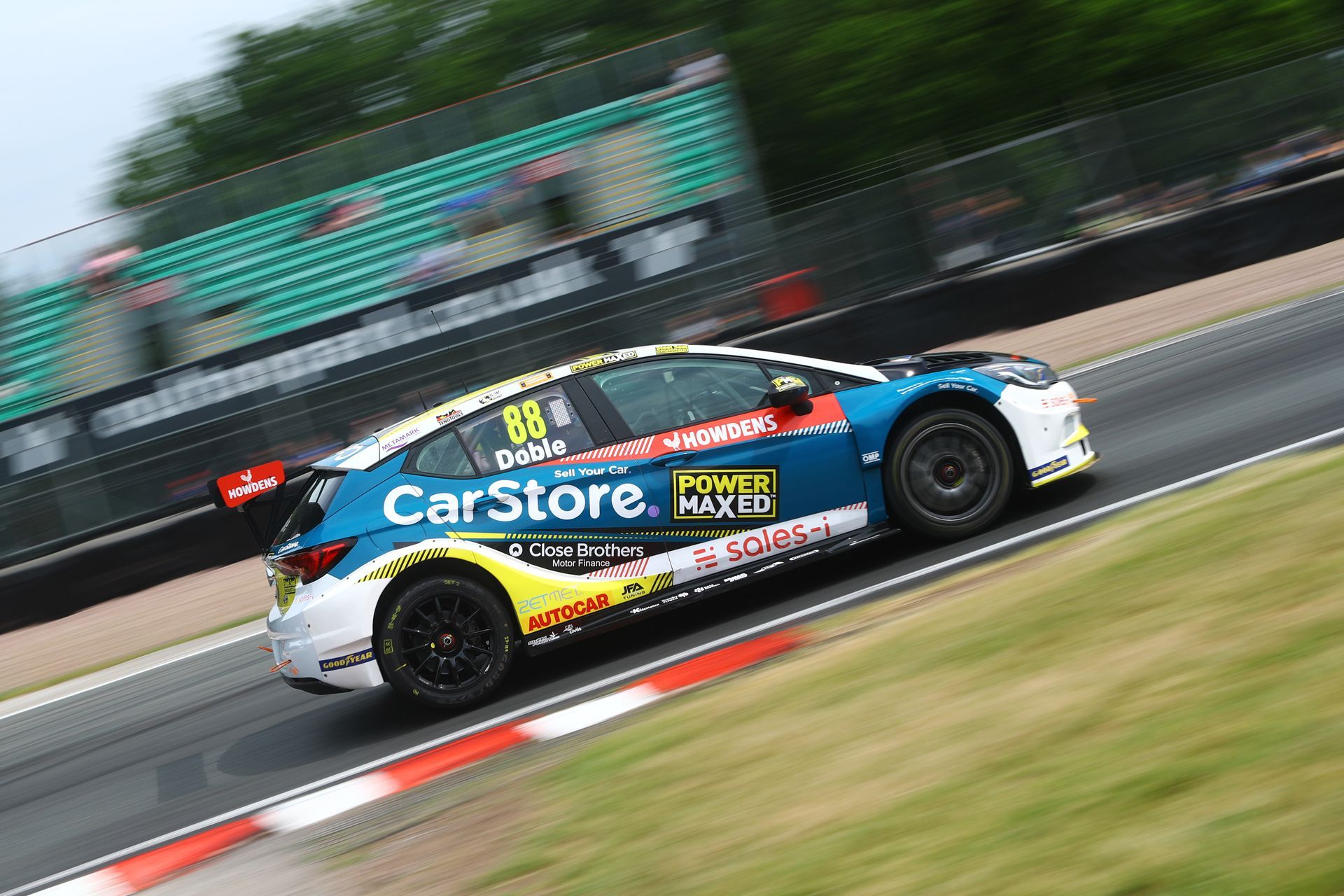 A blue and yellow race car is driving down a race track.