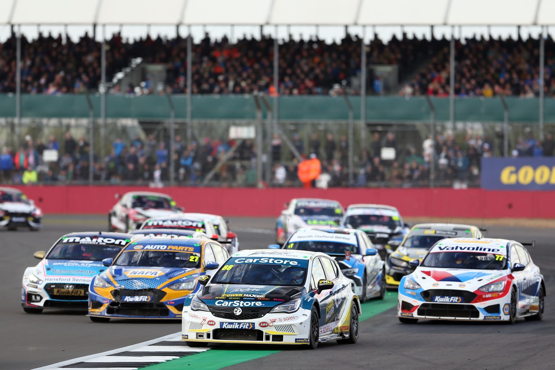 A group of racing cars are driving down a race track.