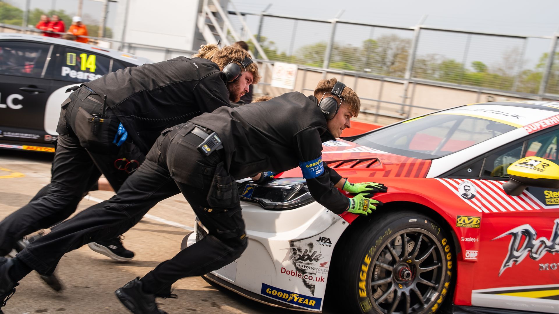 A group of men are pushing a race car on a track.