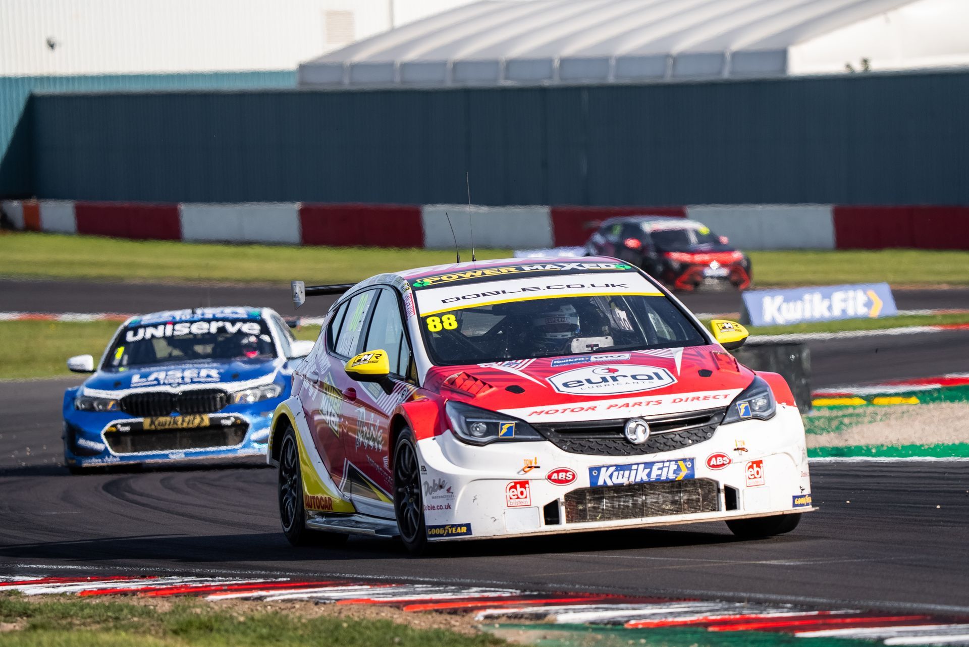 A group of cars are racing on a race track.
