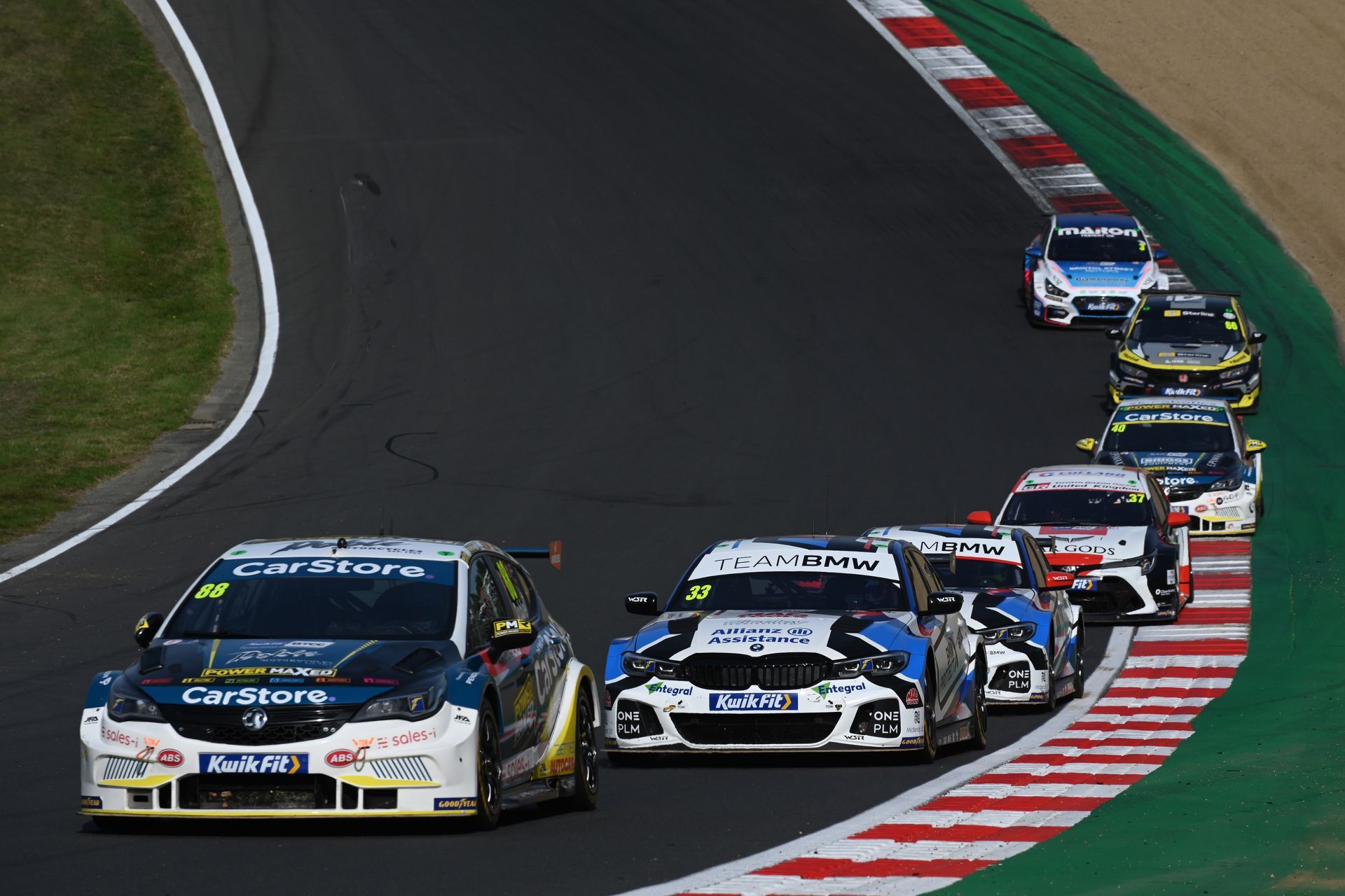 A group of racing cars are driving down a race track.