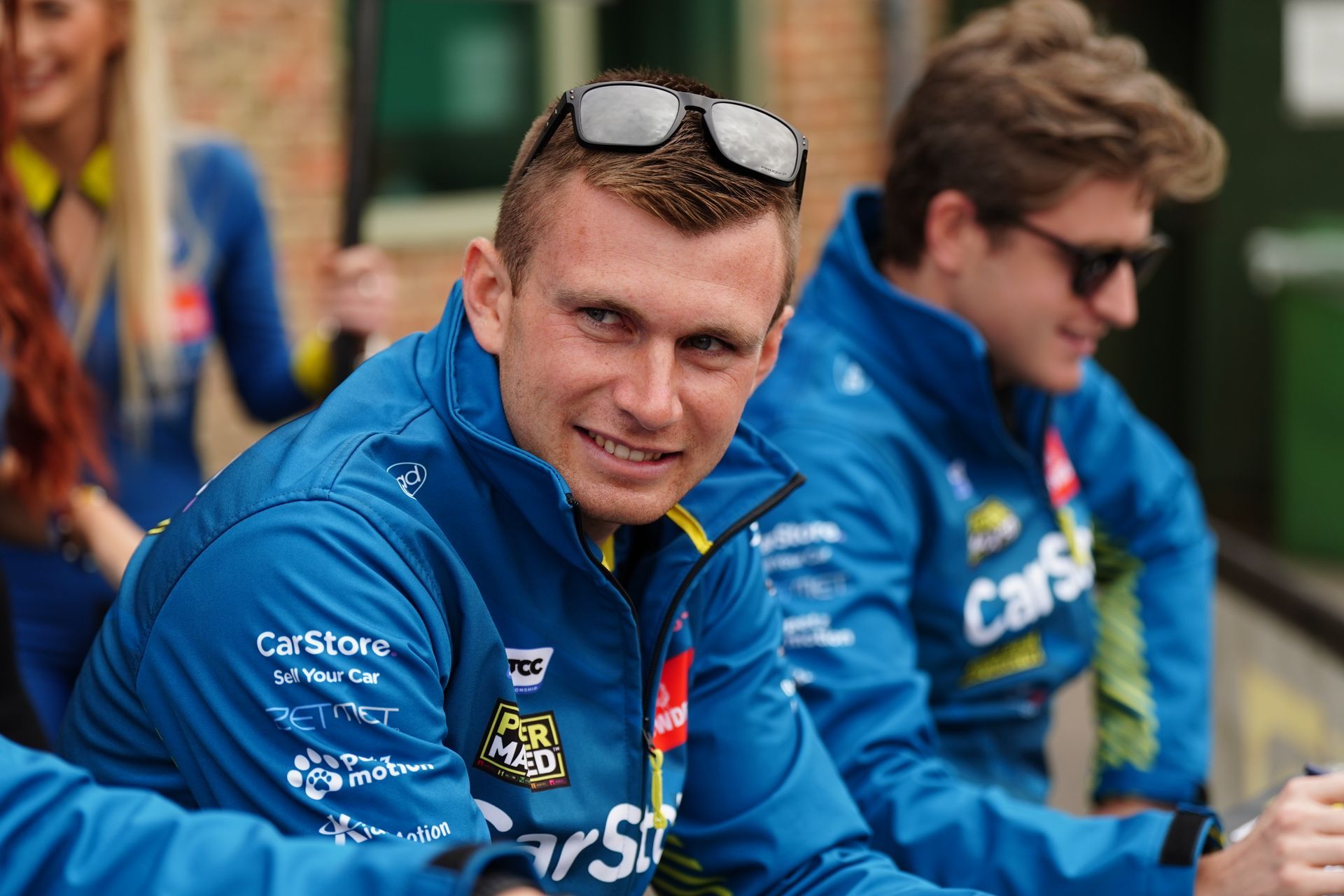 A man wearing sunglasses and a blue jacket with the word cars on it